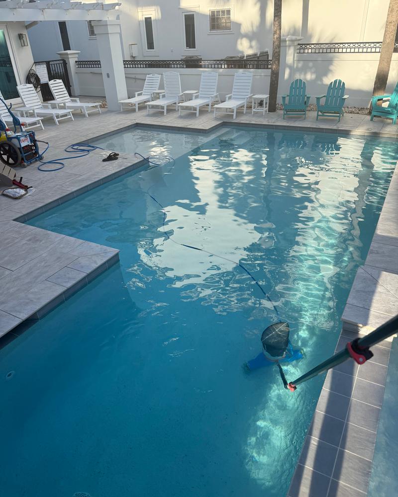 Pool being vacuumed with a pole and vacuum head